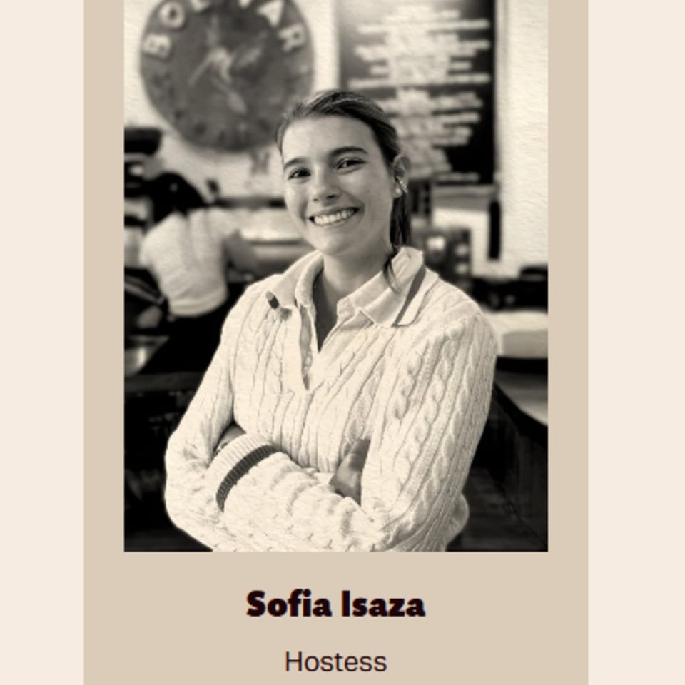 Smiling young woman, Sofia Isaza, hostess at Bolivar Coffee, in a cable-knit sweater.