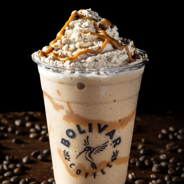 Bolivar Coffee's caramel frappe with whipped cream and caramel drizzle, surrounded by coffee beans.