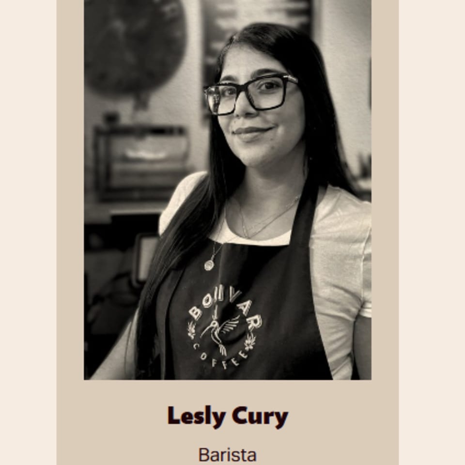 Black and white portrait of Lesly Cury, a smiling barista wearing glasses and a Bolivar Coffee apron.