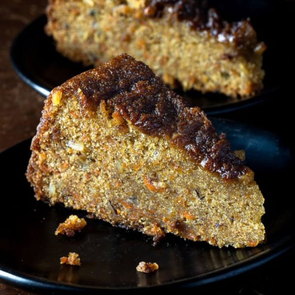 A slice of Bolivar Coffee's carrot cake with a dark, glistening topping on a black plate.