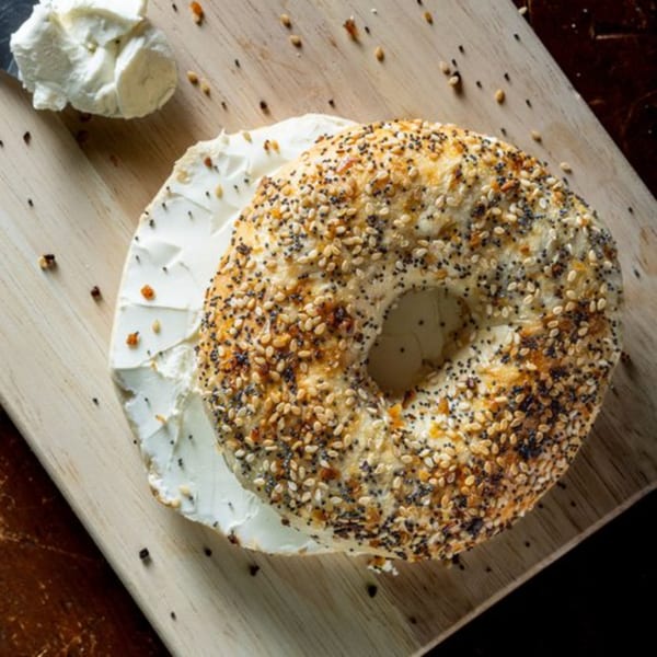 Everything bagel with cream cheese on a wooden board, ready to eat at Bolivar Coffee.
